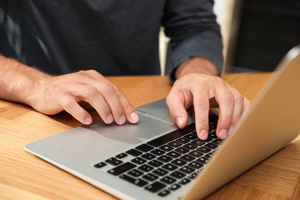 Man using laptop for search at wooden table, closeup - Photo, Image