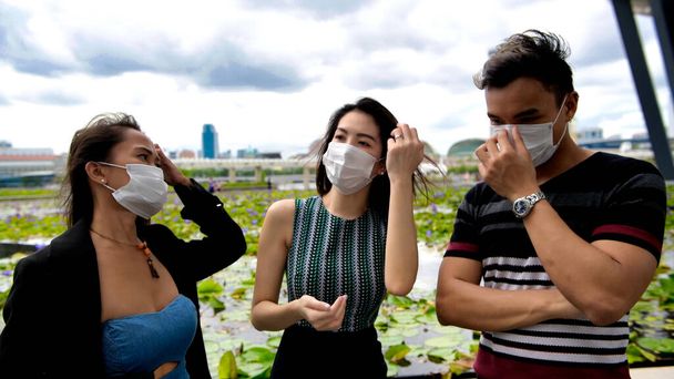 Tři asijské mladé přátele stojící venku ve městě mluví a nosí obličejové masky v covid coronavirus pandemie. - Fotografie, Obrázek