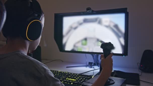 Giovane ragazzo che gioca un simulatore di volo indossando un auricolare - Filmati, video