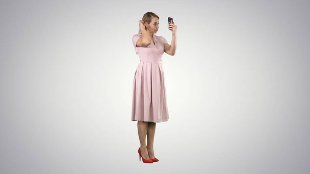Güzellik kadını akıllı telefonuyla kendine bakıyor, bacağını düzeltiyor. - Fotoğraf, Görsel