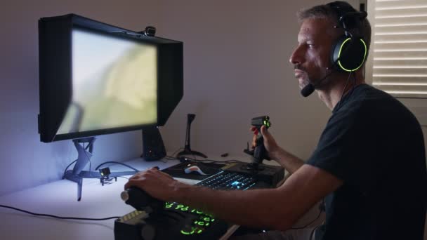 Человек, играющий симулятор полета на компьютере, одетый в наушники - Кадры, видео