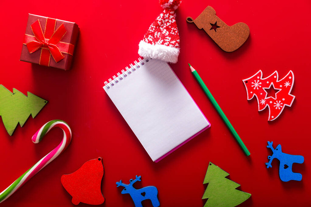 プレゼント、ギフトボックス、手作りの木のおもちゃやテキストの願いのためのペンでメモ帳、上からの眺め、赤背景、クリスマスグリーティングカード。横写真 - 写真・画像