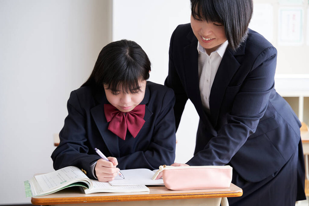A Japanese junior high school girl is taught by her teacher in the classroom - Photo, Image