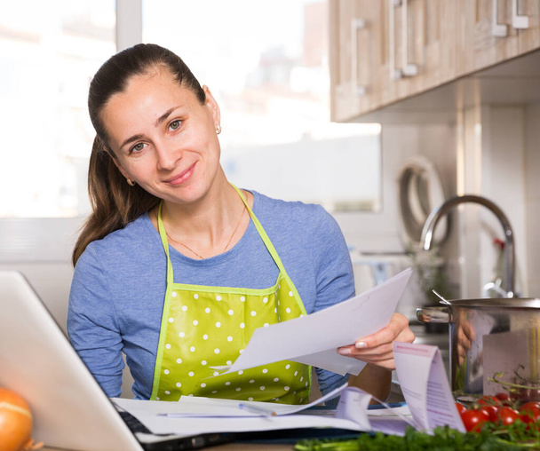Smiling young woman reading recipe in the kitchen - Foto, imagen