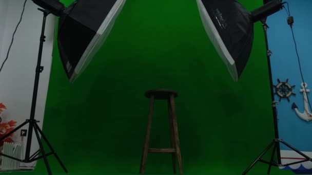 Studio fotograficzne lub wideo z dwoma sześciokątnymi lampami studyjnymi. Zielony ekran i krzesło stałe - Materiał filmowy, wideo