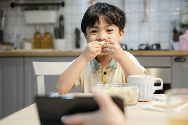 Boy eating dinner and watching video on tablet. - Foto, Imagen
