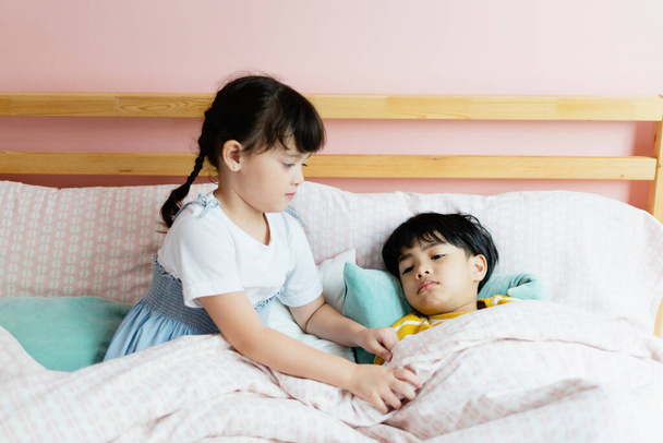 Sister taking care of her sick brother in bedroom with love and care. - Фото, изображение