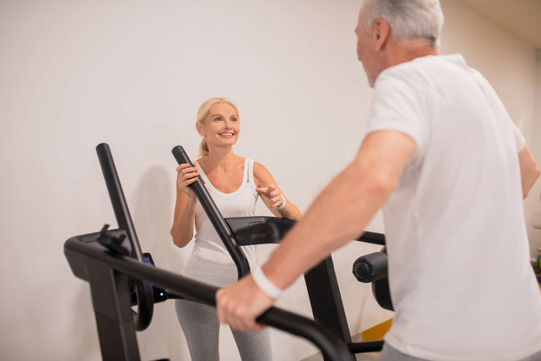 A man and a woman exercising on treadmills and feeling good - Foto, Imagem