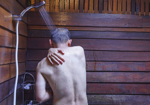 アジア人男性のシャワーで体をきれいにし、裸と水でリラックスシャワーから頭とすべての体に滴、バスルームでアジア人男性入浴. - 写真・画像