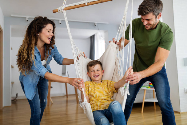 Happy family concept. Beautiful young parents having fun, playing with their son at home. - Photo, image