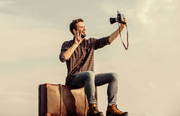 Travel blog. Man sit on suitcase. Handsome guy traveler retro camera. Travel with luggage. Travel blogger. Shooting vlog. Vacation time. Guy outdoors with vintage suitcase. Photojournalist concept - 写真・画像