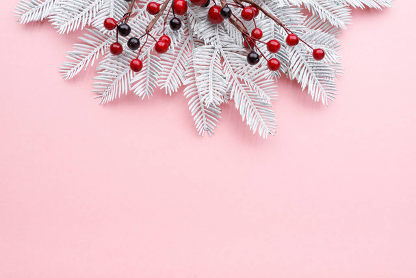 Christmas border with white fir branches and red berries on pastel pink background, copy space - Zdjęcie, obraz