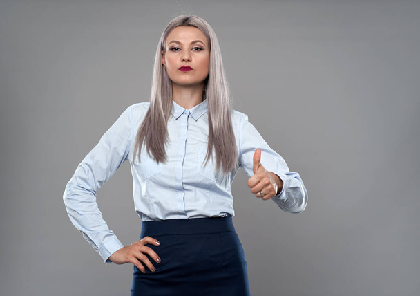 Confident young businesswoman showing thumbs up, gray background - Fotoğraf, Görsel