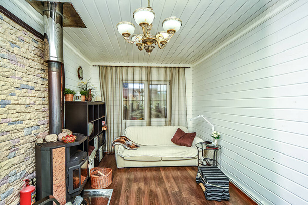 Das Interieur des Wohnzimmers in einem hölzernen Landhaus besteht aus Birkenholz-Klappplatten, die in einem hellen Ton gestrichen sind - Foto, Bild
