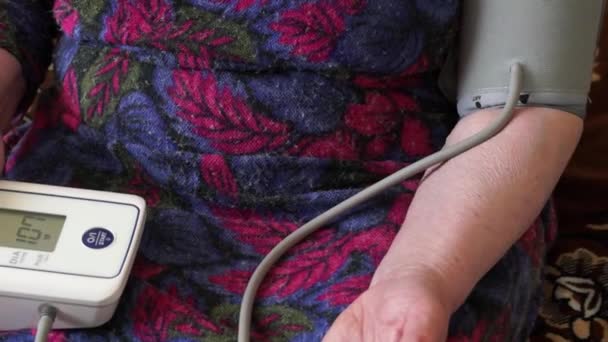 comprobar su ritmo cardíaco con un tonómetro automático de muñeca. una anciana mide su presión arterial. - Imágenes, Vídeo