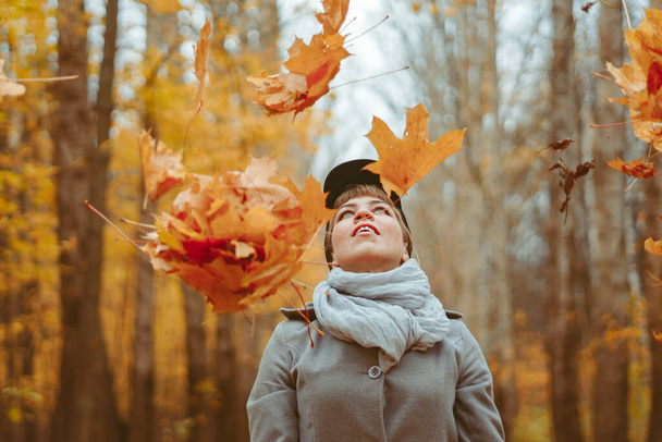Mooie jonge vrouw zit in de herfst bos in gele blouse met esdoorn bladeren en geniet van het leven. Vrijheid. - Foto, afbeelding