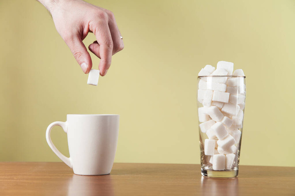 Hand puts sugar cubes on coffee cup. - Foto, immagini