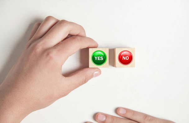 Hand showing Yes and No buttons in wooden cube. - Zdjęcie, obraz