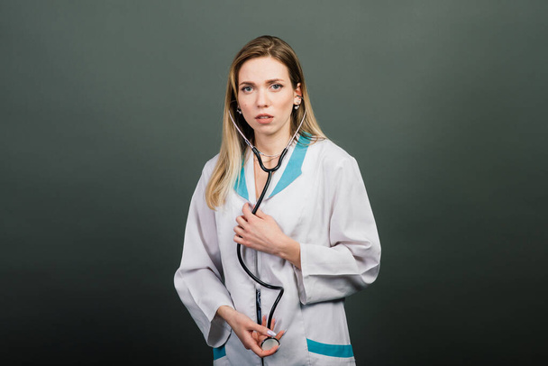 Portrait of woman doctor with stethoscope looking at camera on grey background, healthcare - Foto, afbeelding