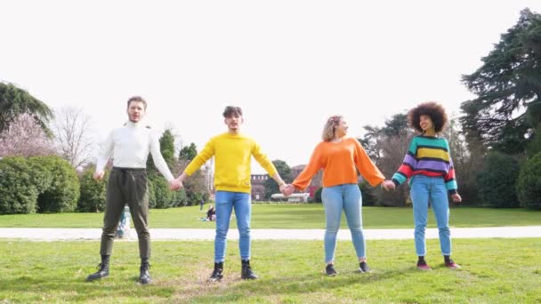 Hidasliikkeinen ryhmä ihmisille ystäviä hyppäämällä ulkona taustavalo innoissaan tunne vapaasti juhlii elämää ja nauttia aikaa yhdessä keväällä puistossa - Materiaali, video