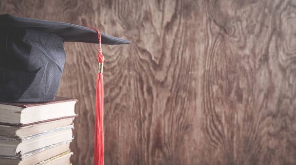 Berretto graduato con libri sullo sfondo in legno. Istruzione - Foto, immagini