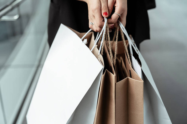 Primo piano mano della donna che tiene borse di carta shopping - concetto di shopping. - Foto, immagini