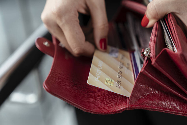Ruka ženy vytáhnout kreditní kartu z červené kabelky - Nákupní koncept. - Fotografie, Obrázek