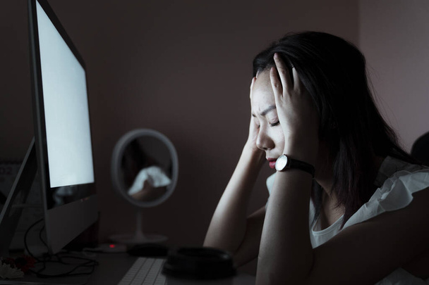 Азійська молода жінка тай втомилася працювати понаднормово перед комп'ютером. Здорова мігрень, безсоння, головний біль. - Фото, зображення