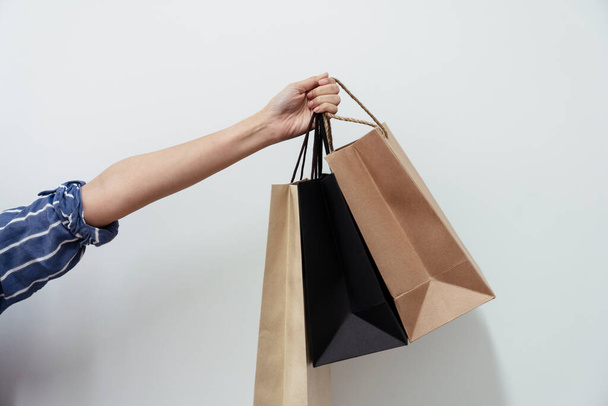 Hand of shopping lover woman holding shopping paper bags isolated on white background. - 写真・画像