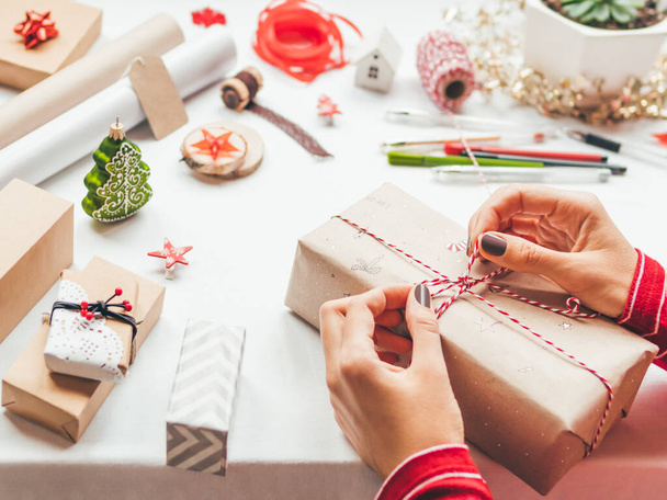 Table with Christmas decorations. Woman draws New Year symbols on craft paper and wraps presents. Flat lay with copy space. - Foto, Imagem