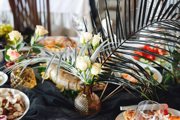 Primer plano de mesa festiva con copas de vino, comida y helecho fresco. Banquete de selebración en blanco y negro - Foto, Imagen