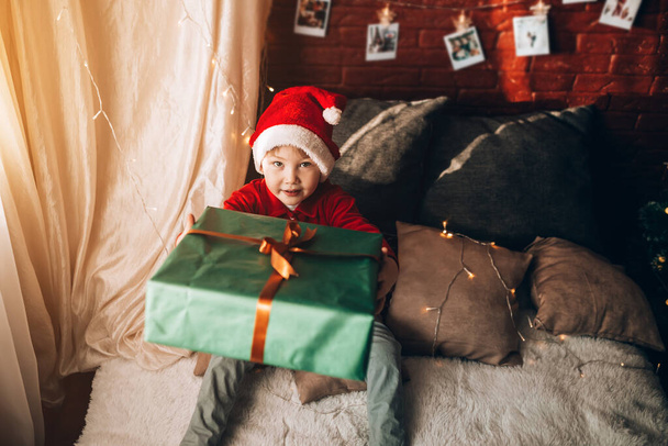 緑色のパッケージに大きな箱を持っている少年と贈り物と弓。クリスマス気分. - 写真・画像