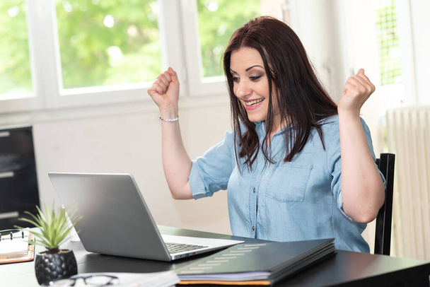 Mujer atractiva joven recibiendo buenas noticias en el ordenador portátil - Foto, Imagen