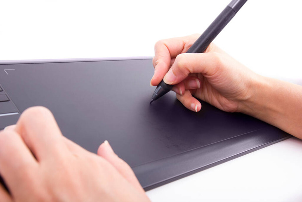 Close up of a hand holding a pen and drawing on a tablet surface retouching, drawing or making a graphic design - Foto, imagen