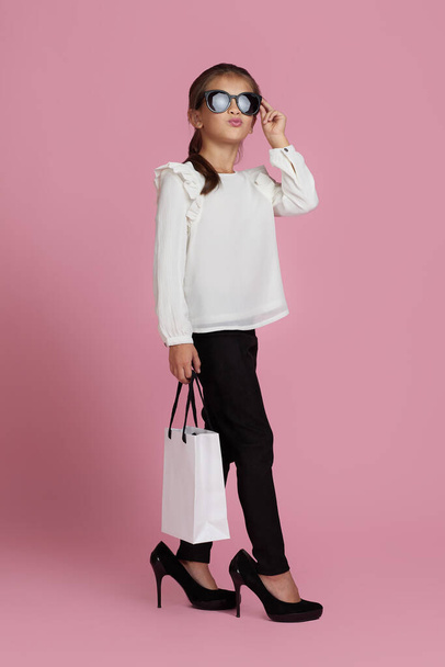 child girl in sunglasses is holding shopping bags - Foto, imagen