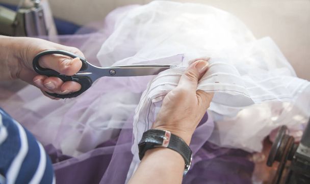 Caucasian seamstress cutting fabric with scissors. - Фото, зображення