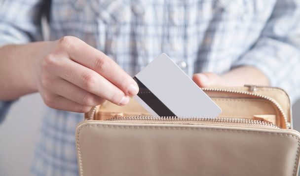 Κορίτσι κατέχει και να εισαγάγετε πιστωτική κάρτα στο πορτοφόλι της. - Φωτογραφία, εικόνα