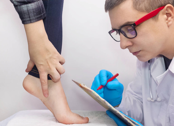 Een orthopedisch chirurg onderzoekt een vrouwenbeen. Voetpijn, peesverstuikingen, ontsteking, platte voeten, bursitis, fasciitis. Behandeling van voetziekten. De dokter onderzoekt - Foto, afbeelding