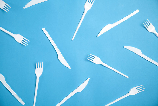 Fourchette et couteaux en plastique sur fond bleu. - Photo, image