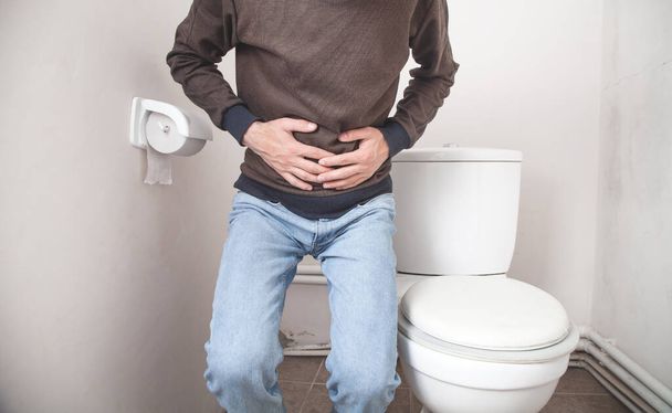 Белый мужчина в туалете. Концепция боли в животе, диареи - Фото, изображение