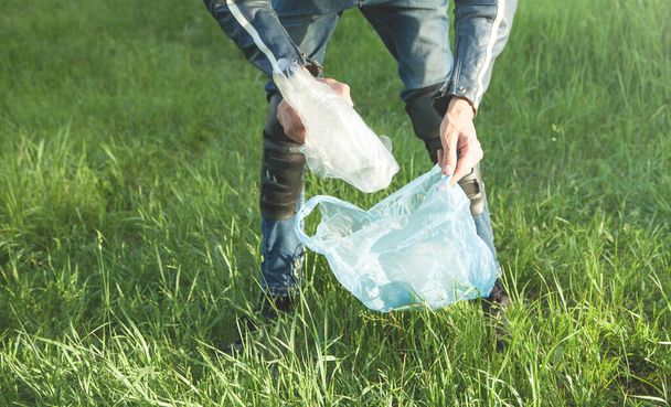 Man picks up a plastic bag from grass park. - Fotó, kép