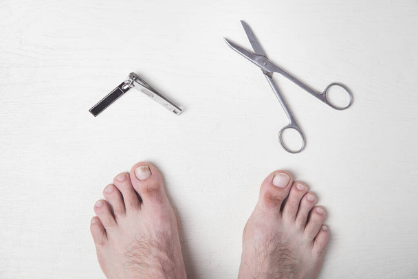 Male foots with a clipper and scissors. Cutting nails - Photo, Image