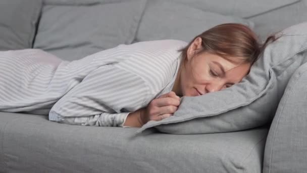 Κουρασμένη γυναίκα νοικοκυρά πέφτει στον καναπέ χωρίς δύναμη και αποκοιμιέται κατά τη διάρκεια της ημέρας στο σπίτι - Πλάνα, βίντεο