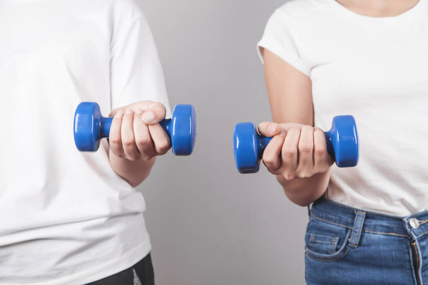 Girls holding dumbbells in gray background. - Foto, immagini