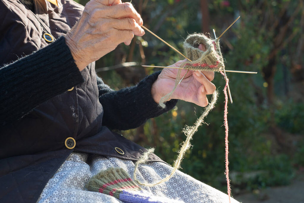 Primo piano della mano di una donna anziana usando gli aghi per lavorare i calzini tradizionali di lana serba - Foto, immagini