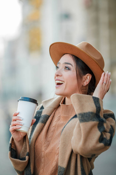 Közelkép gyönyörű fiatal nő kalapban kávéval sétál egy európai városban - Fotó, kép