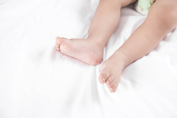 Ноги маленького ребенка лежат на кровати. - Фото, изображение