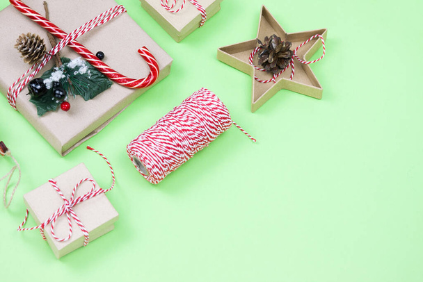 Christmas eco friendly packaging gifts on green, eco christmas holiday concept, eco decor festive winter background. Present with candy and fir-tree, paer boxes and wooden tree toy on green - Foto, Imagem