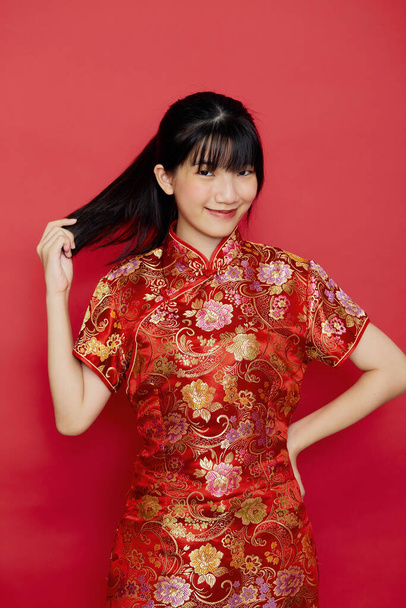 Aranyos fiatal ázsiai nő visel cheongsam cselekvési kínai újév koncepció piros alapon - Fotó, kép