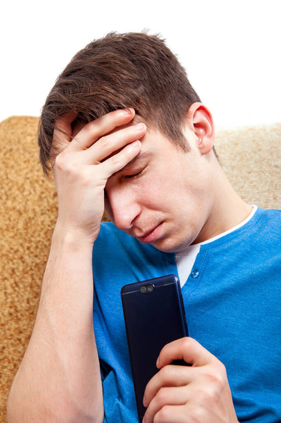 Sad Young Man with a Phone on the Sofa at the Home - Foto, Bild